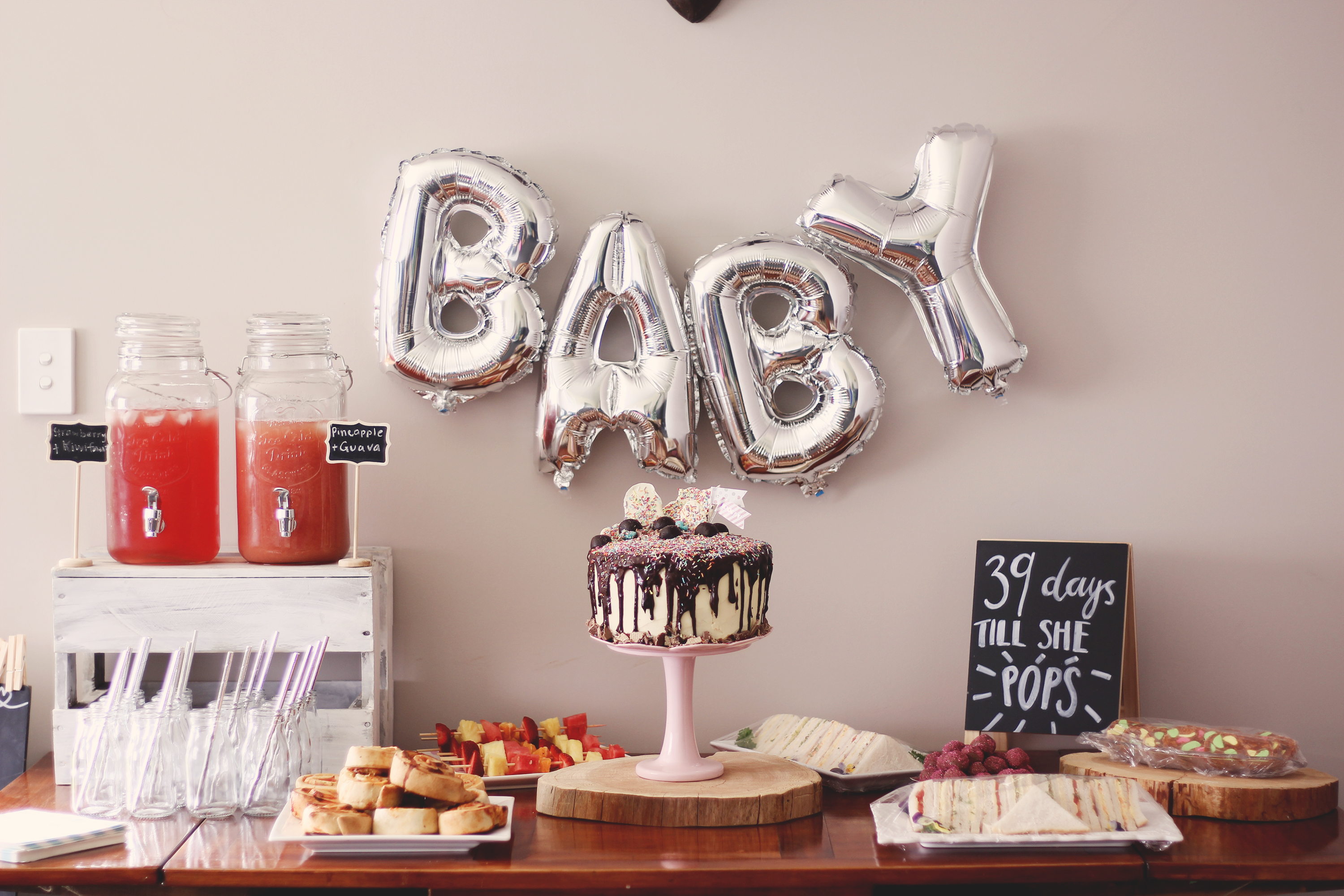 Check out this fun, boho baby shower. Foil balloons, wooden rounds and a cake to die for. plus free printable baby shower games.
